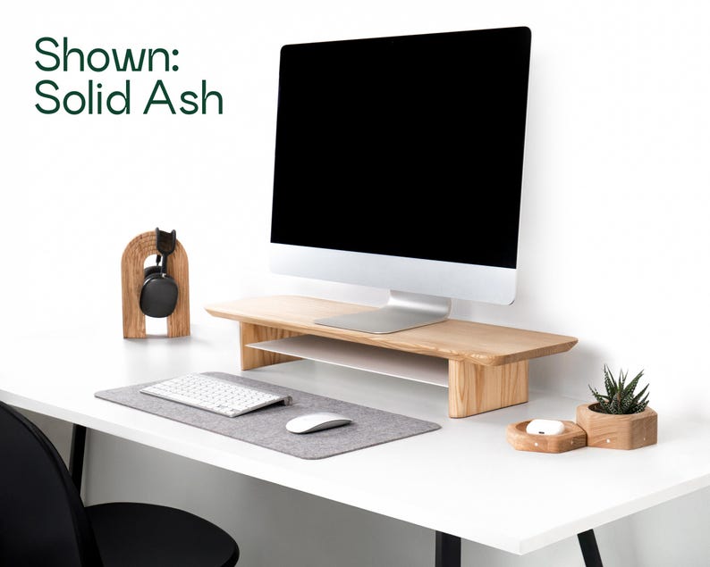 a modern, minimalist workspace with a white desk, a computer monitor, a keyboard, a mouse, and a potted plant.