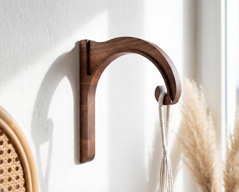 A wooden hanging hook is mounted on a white wall, with a woven basket visible in the background.