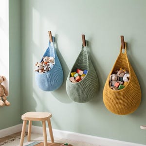 A cozy children's room with a window, three hanging baskets filled with toys, and a wooden stool.