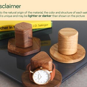 a wooden watch stand with a wooden watch placed on top of it, along with a book titled "The Catcher in the Rye" by J.D. Salinger.