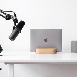 a white desk with a microphone, a laptop, and a speaker on it.