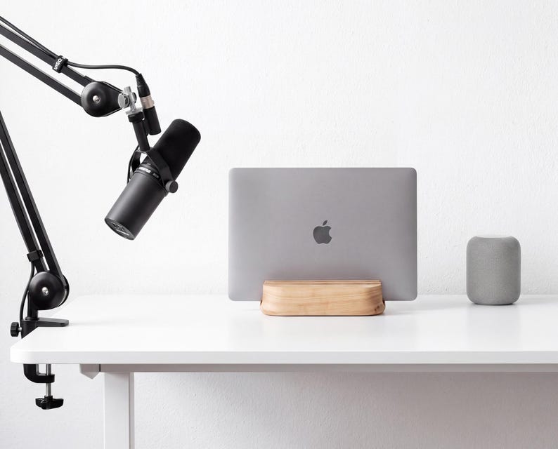 a white desk with a microphone, a laptop, and a speaker on it.