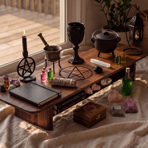 a wooden table with various items related to spells and rituals, including a cauldron, a crystal ball, a pentagram, and a book titled "The Occult Book".