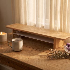 a wooden table with a candle, a mug, and a bowl of flowers, all placed on it.