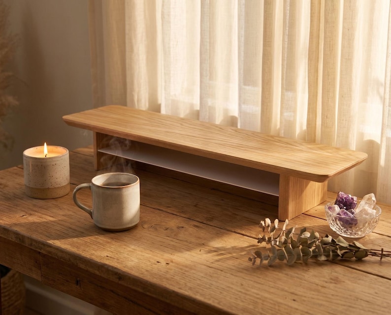 a wooden table with a candle, a mug, and a bowl of flowers, all placed on it.