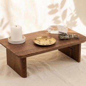 a wooden table with a candle, a crystal, and a plate with a crescent moon design.