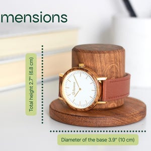 A wooden watch stand holding a gold-colored watch with a brown leather strap. The image also includes dimensions and a description of the watch and its stand.