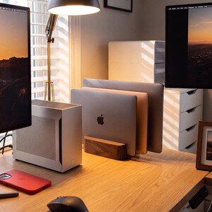 a well-organized workspace with a wooden desk, a laptop, a monitor, and a mouse. The desk has a wooden stand that holds the laptop and monitor, creating a neat and tidy appearance.