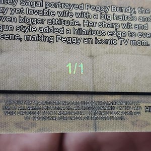 May include: A trading card with text about Katey Sagal as Peggy Bundy. The card has a textured background and the number "1/1" in the center. The card also features the logos "HM" and "HITSCARDS.COM".