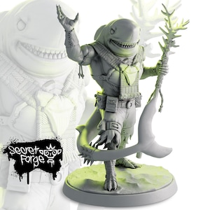 May include: A gray painted miniature figurine of a shark-human hybrid holding a staff with a branch at the top. The figure is wearing a scarf and has a belt with pouches. The figure is standing on a round base.