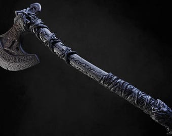May include: A black axe with a wooden handle wrapped in rope and a wolf head design at the end. The axe head is decorated with intricate carvings and the handle has the word "REKVI" carved into it.