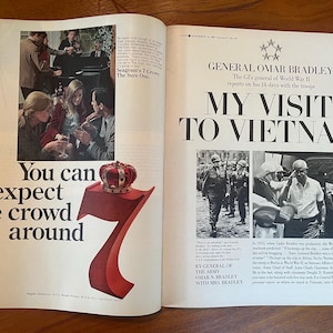May include: A vintage magazine spread featuring a Seagram's 7 Crown advertisement on the left with a large red number seven topped by a crown, and an article on the right titled General Omar Bradley My Visit to Vietnam with black and white photos.
