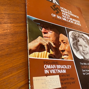 May include: A vintage LOOK magazine cover featuring a brown background with white and black text. The cover displays a swastika, a photograph of two men, and a portrait of a young girl. A white mailing label is affixed to the lower section.