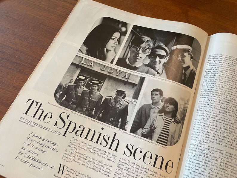 May include: A vintage magazine page titled The Spanish scene by Chandler Brossard, featuring black and white photographs of people and uniformed officials in Spain. The layout includes columns of printed text and multiple candid images.