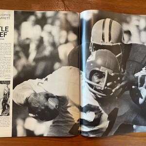 May include: A black and white magazine spread featuring the headline Kansas City's Mike Garrett Big Little Chief by Gerald Astor. The page shows a photograph of two football players in helmets and jerseys engaged in a play on the field.