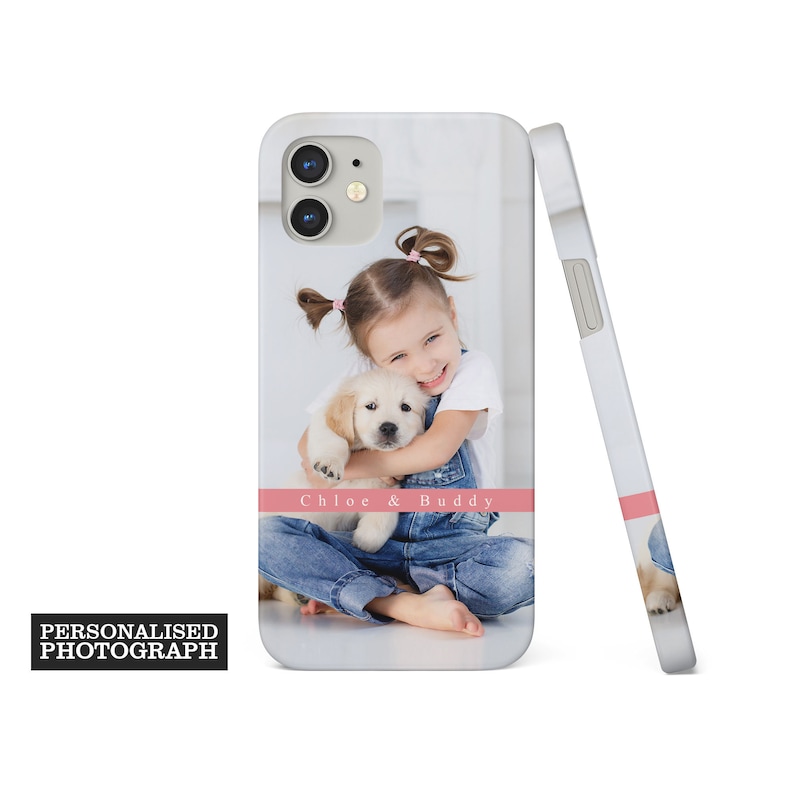 Op de afbeelding: Witte iPhone-hoes met een foto van een jong meisje dat een golden retriever puppy knuffelt. De hoes heeft een roze streep met de tekst "Chloe & Buddy". De woorden "Personalised Photograph" staan in een zwarte doos.