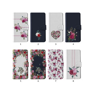 Puede incluir: Ocho fundas para teléfono con diseños florales. Las fundas son blancas y azul marino, con rosas rosas y rojas. Algunas fundas presentan un arreglo floral en forma de corazón, mientras que otras tienen un patrón floral completo o un solo ramo de rosas.