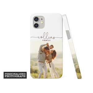 Op de afbeelding: Witte telefoonhoes met een familiefoto en de naam "Collins" in sierlijke letters. De hoes is gepersonaliseerd met een familieportret en de woorden "Personalised Photograph" zijn gedrukt op een zwarte rechthoek.