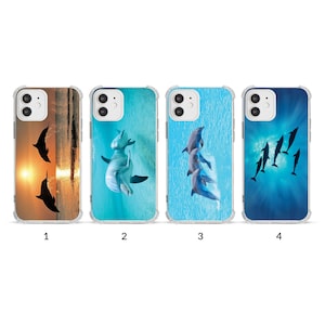 May include: Four clear phone cases with different dolphin designs. One case features silhouettes of dolphins against a sunset. The other cases show dolphins in a turquoise and blue ocean setting. Each case has a clear protective bumper.