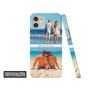 Op de afbeelding: Een lichtblauwe telefoonhoes met twee strandfoto's. De bovenste foto toont een stel dat op het strand loopt en de onderste foto toont een stel dat op het strand zit. Het woord "forever" is cursief geschreven. De tekst "PERSONALISED PHOTOGRAPH" staat in een zwarte rechthoek.