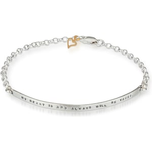 Puede incluir: Un brazalete de plata con una cadena delicada y un pequeño charm de corazón de oro. El brazalete tiene una banda curva con la inscripción "My heart is and always will be yours."