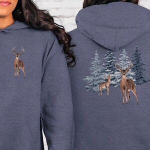 May include: A navy blue hoodie with a deer graphic on the front and back. The front features a single deer, while the back showcases two deer and evergreen trees. The design is printed on a soft, comfortable fabric.