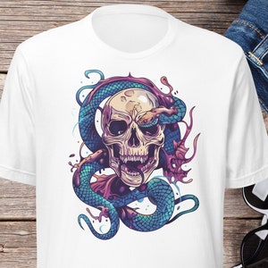 May include: White t-shirt featuring a colorful illustration of a skull entwined by a blue and purple serpent. The design has a tattoo-style aesthetic. The word "WHITE" is visible in an orange box on the left side of the shirt.