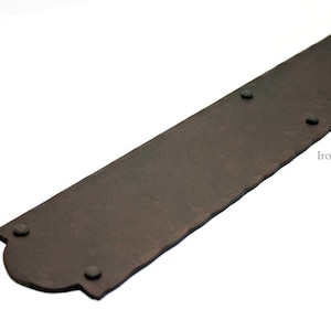 Peut inclure: Une longue plaque rectangulaire en métal avec un bord festonné et une finition brun rustique. La plaque comporte quatre rivets en métal noir espacés uniformément.