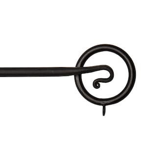 May include: Black metal curtain rod finial with a circular design and a decorative swirl. The finial has a small hook at the bottom.