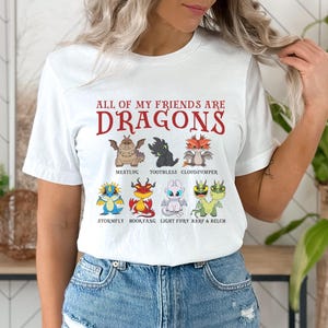 May include: White t-shirt with the text "ALL OF MY FRIENDS ARE DRAGONS" printed in red. The shirt features cartoon images of dragons from the How to Train Your Dragon franchise.