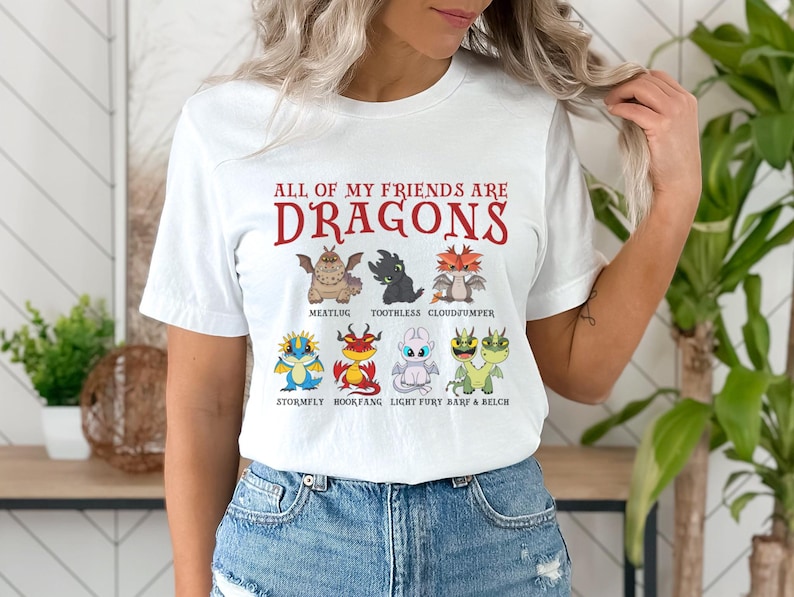 May include: White t-shirt with the text "ALL OF MY FRIENDS ARE DRAGONS" printed in red. The shirt features cartoon images of dragons from the How to Train Your Dragon franchise.