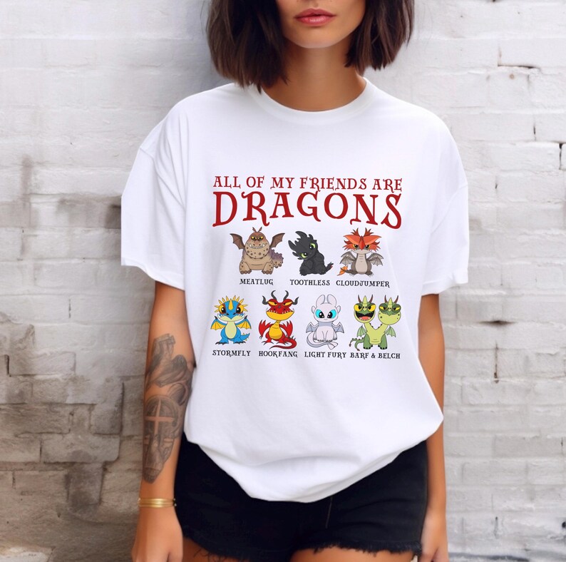 May include: White t-shirt with the text "ALL OF MY FRIENDS ARE DRAGONS" in red. The shirt features cartoon images of dragons from the How to Train Your Dragon franchise, including Toothless, Meatlug, Cloudjumper, Stormfly, Hookfang, Light Fury, Barf and Belch.