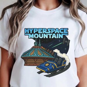 May include: White t-shirt with a graphic of the Hyperspace Mountain ride. The design shows the ride's name in blue, a roller coaster car, and a space scene with stars and a spaceship. The shirt has a classic crew neck.