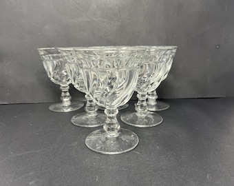 May include: Set of six clear glass stemmed drinking glasses with a cut glass design. The glasses have a wide bowl and a short stem.
