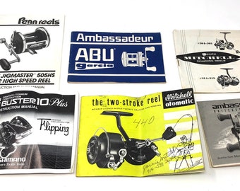 May include: A collection of vintage fishing reel manuals and promotional materials. The items include manuals for Penn Reels, ABU Garcia, Mitchell, and Shimano fishing reels. The manuals are in various colors and feature illustrations of the reels.