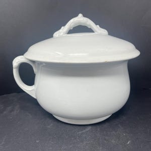 May include: White porcelain chamber pot with a lid and a handle. The lid has a decorative handle.