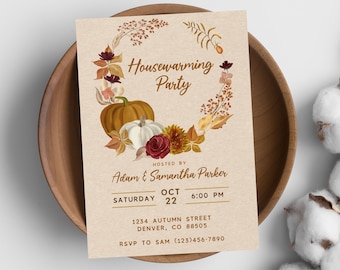 May include: A housewarming party invitation with a fall theme. The invitation features a wreath of autumn leaves, pumpkins, and flowers. The text reads "Housewarming Party" and includes the host's names, date, time, and address. RSVP information is also included.
