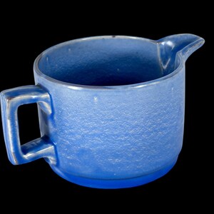 May include: A blue ceramic creamer with a textured surface and a handle.