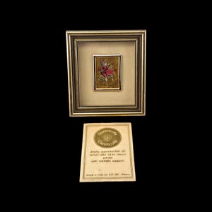 Peut inclure: Une œuvre d'art encadrée représentant un arrangement floral aux tons rouges, violets et verts. L'œuvre est placée sur un fond doré et encadrée dans un cadre doré. Un certificat est en dessous.