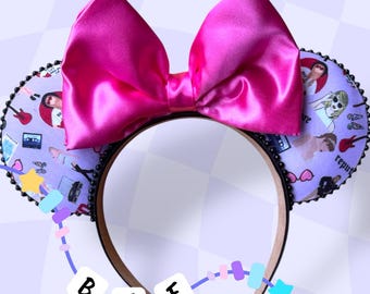 May include: Pink satin bow headband with a purple and white patterned fabric featuring images of a singer and musical instruments. The headband has black beads around the edges.