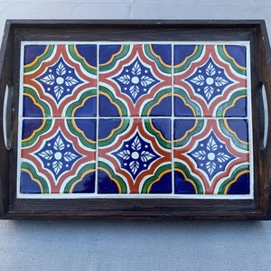 May include: A wooden serving tray with a tile inlay. The tiles are blue, red, green, and yellow with a white floral pattern.