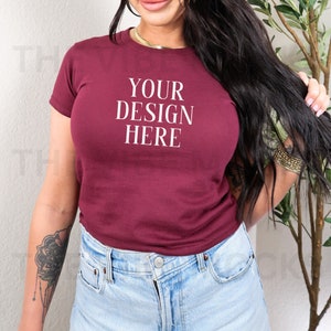Può includere: Una maglietta corta color bordeaux con la scritta "YOUR DESIGN HERE" stampata in bianco sul davanti.
