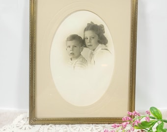 Retrato infantil vintage de la década de 1940 en marco de metal dorado, 7x9 pulgadas, fotografía antigua en sepia de hermano y hermana con paspartú ovalado.