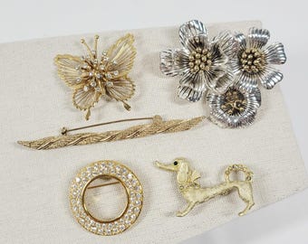 Lote de 5 broches vintage en tonos dorados y plateados: mariposa, perro salchicha y barra de corona.