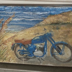 May include: A blue vintage motorcycle on a beach with tall grass and a blue ocean in the background.