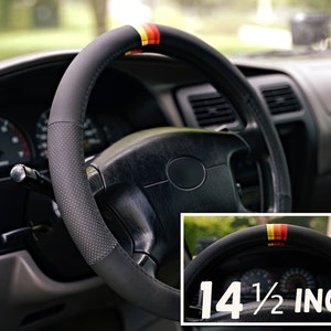 May include: Black leather steering wheel cover with red, yellow, and white stripes. The cover is 14 1/2 inches in diameter.