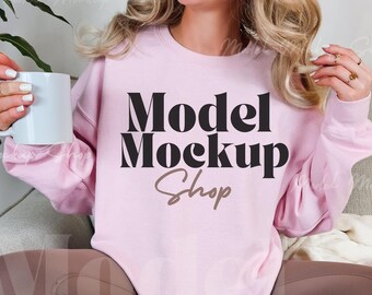 Könnte beinhalten: Ein rosa Sweatshirt mit dem Text "Model Mockup Shop" in schwarzer und brauner Schrift.