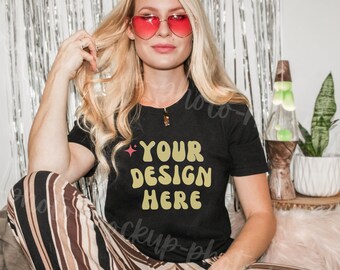 Puede incluir: Una mujer con una camiseta negra con el texto "YOUR DESIGN HERE" en letras amarillas. Lleva gafas de sol en forma de corazón y tiene el pelo largo y rubio.