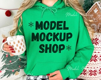 May include: A green hooded sweatshirt with the text "MODEL MOCKUP SHOP" in black with a snowflake on either side of the text.