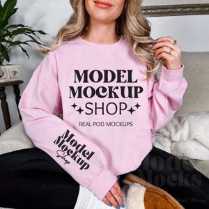 May include: A pink sweatshirt with the text "MODEL MOCKUP +SHOP+ REAL POD MOCKUPS" and "Model Shop" on the sleeve.